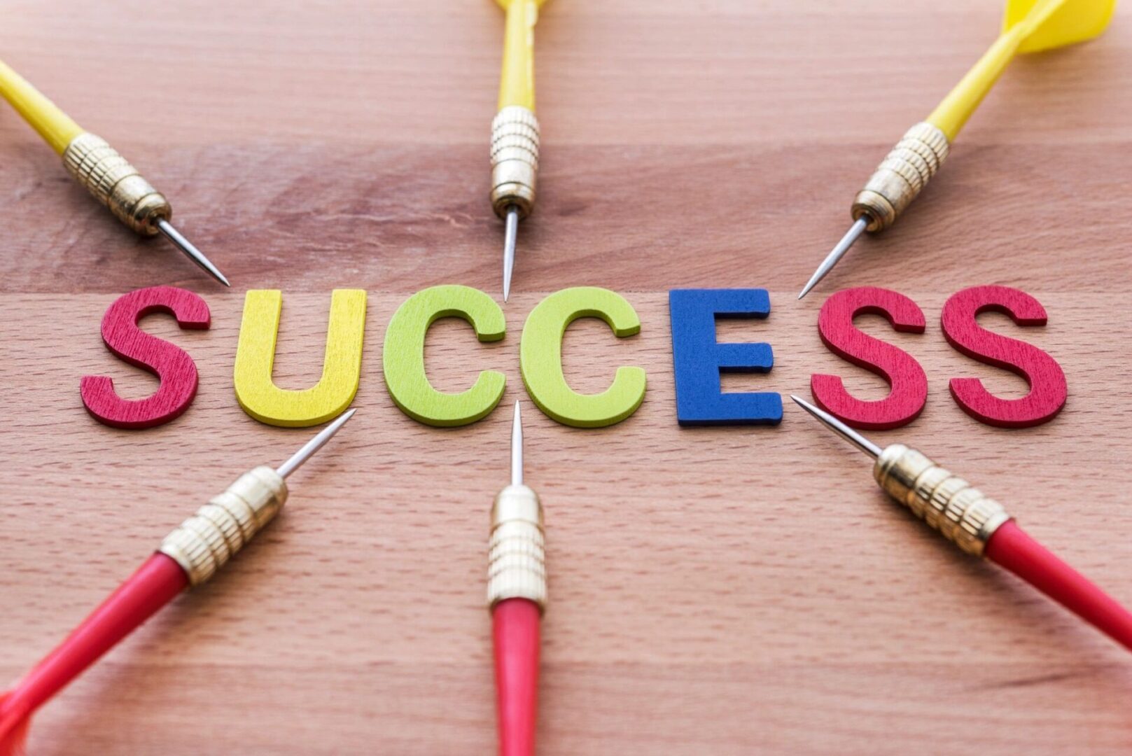 A wooden table with four darts and the word success.